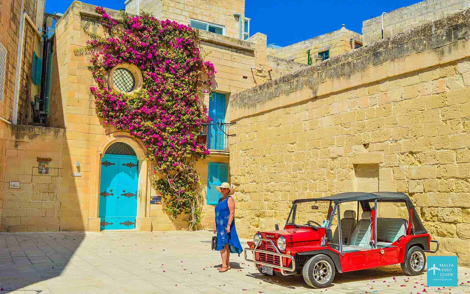 A woman posing in front of a popular Instagrammable house in Mdina Malta.