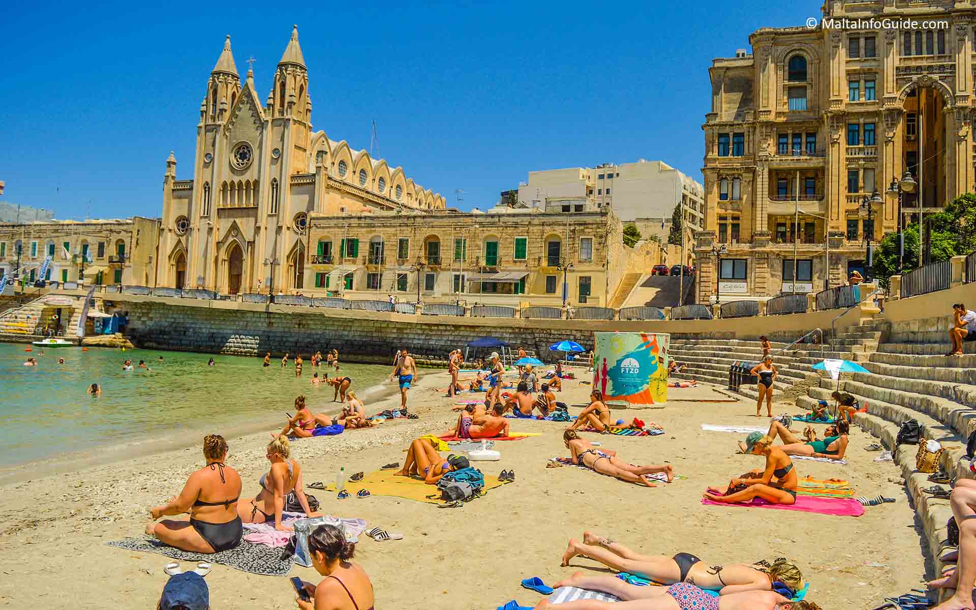 People sunbathing at Balluta bay beach Malta