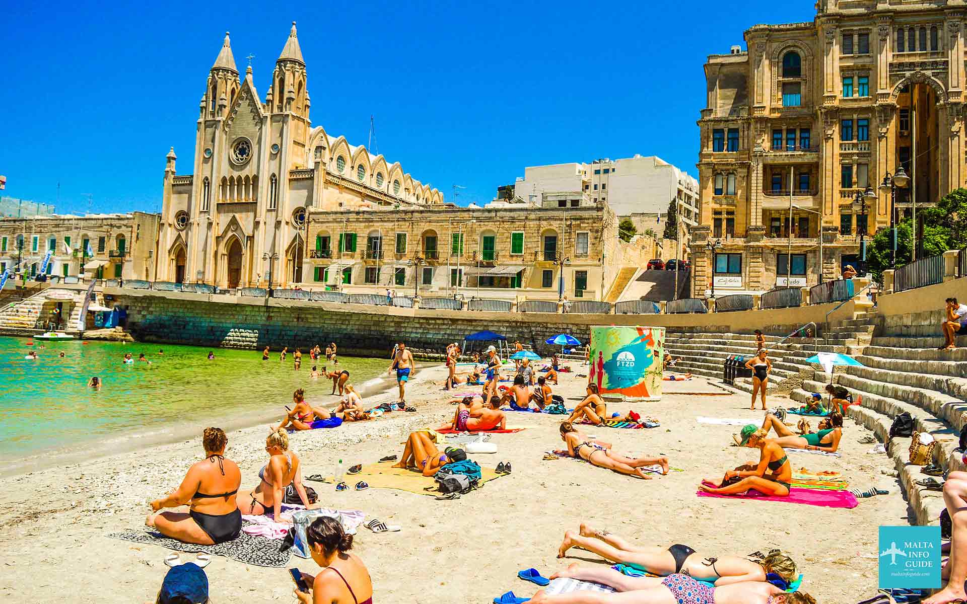 People sunbathing on Balluta bay Malta.