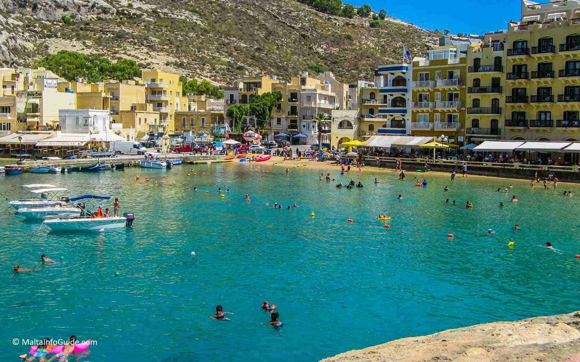 A view of the tiny Xlendi bay while people swimming in the sea
