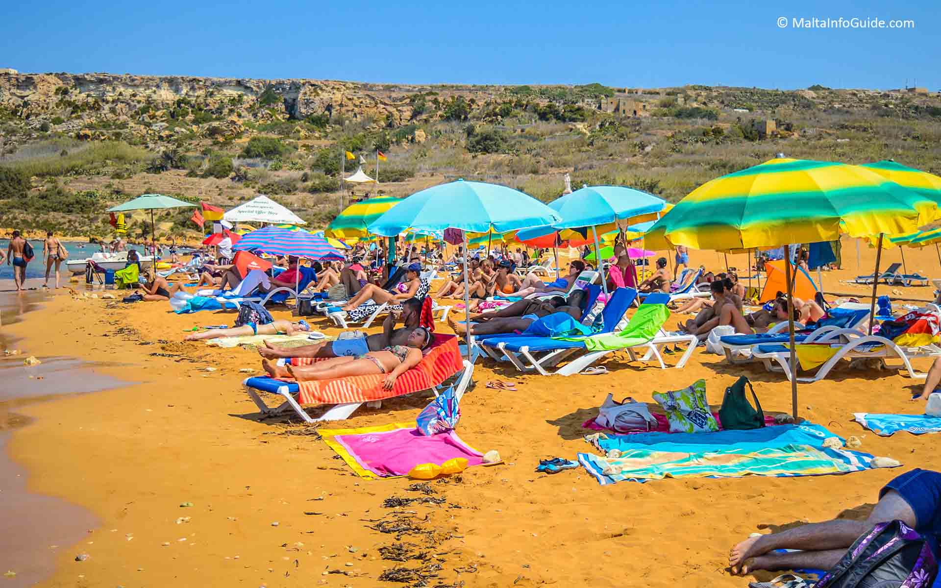 People sunbathing on deckchairs at Ramla Hamra bay.