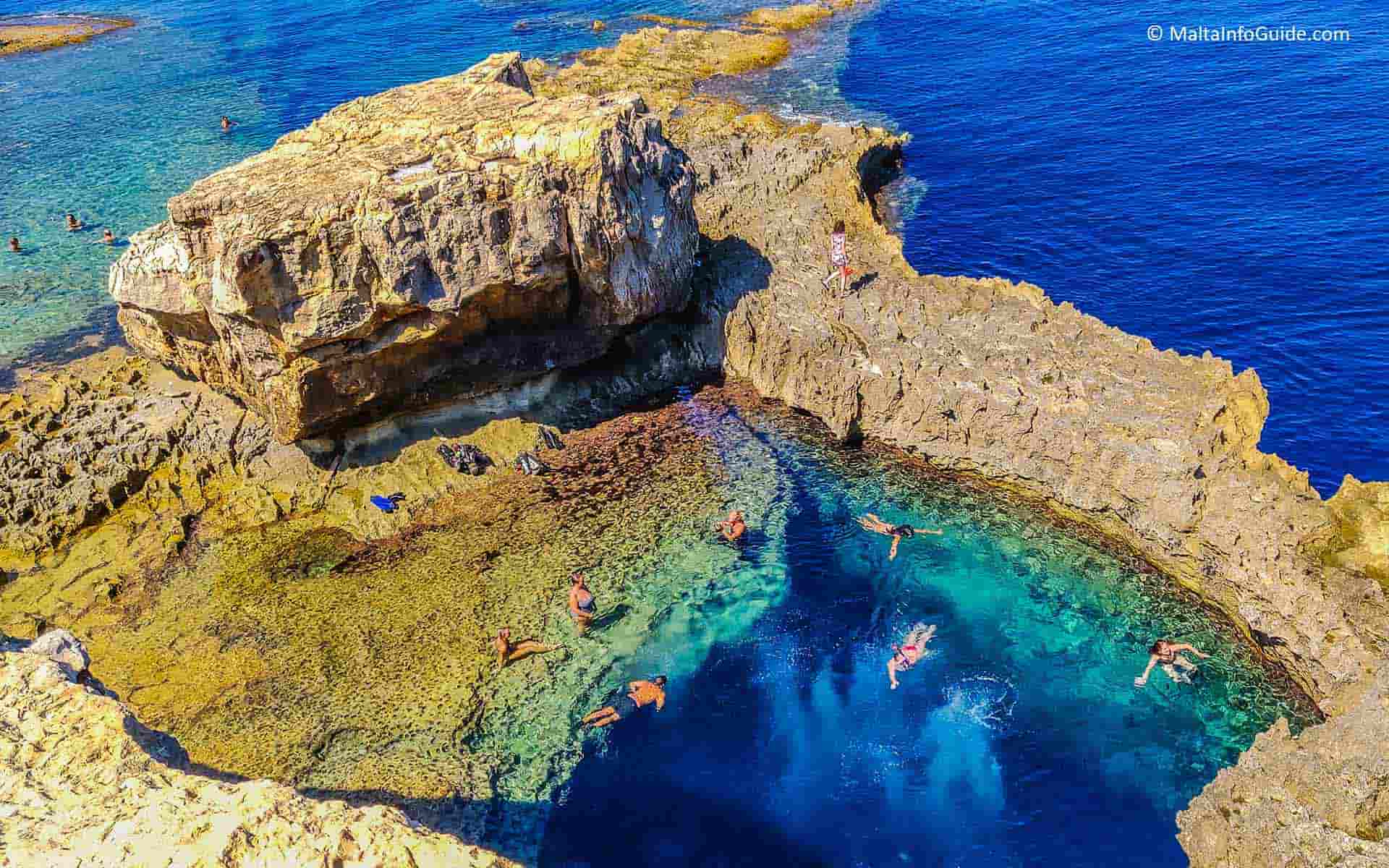 A few people swimming at the Blue Hole in Gozo. Visiting this hidden gem makes you capture the best Gozo beaches photos.