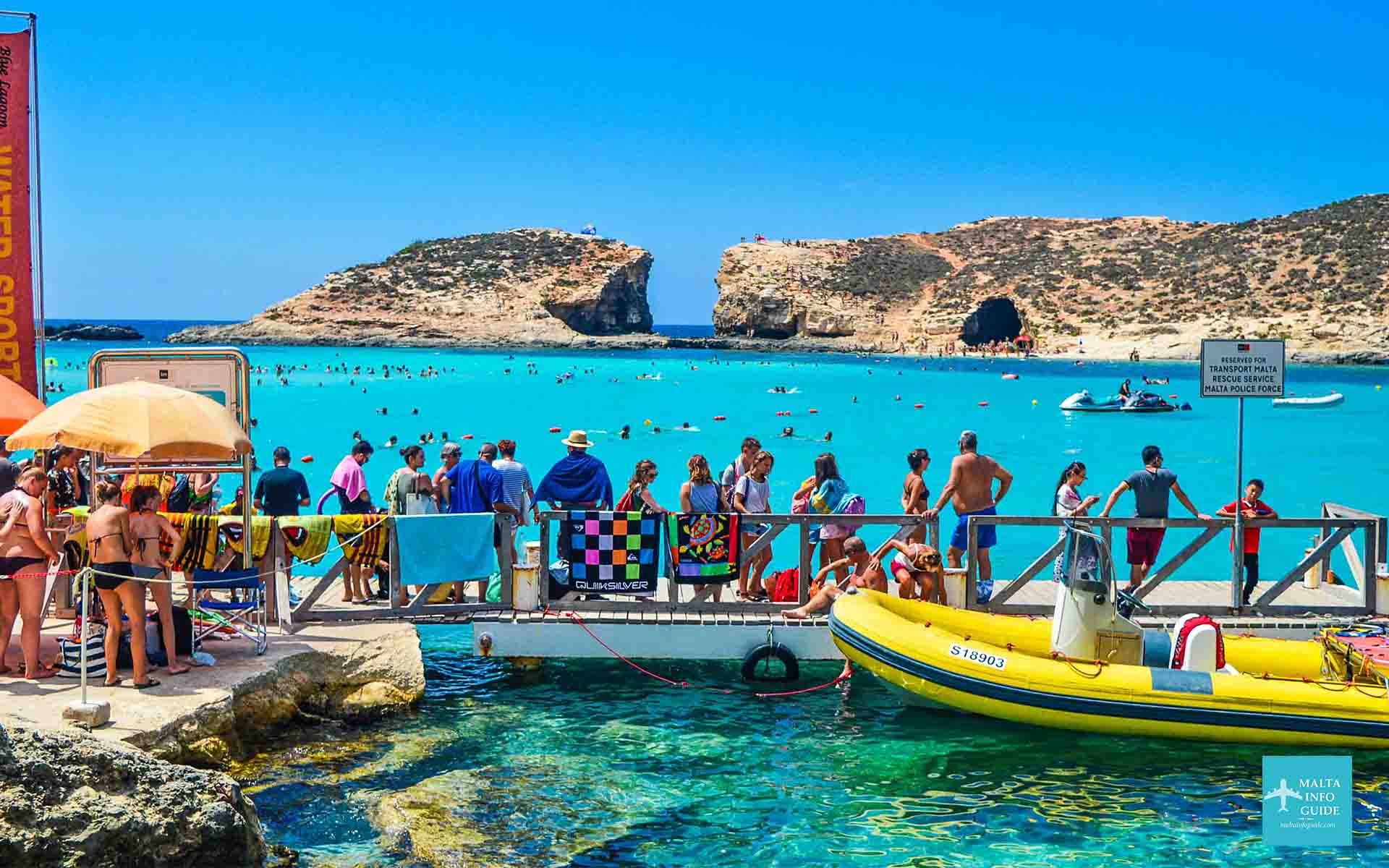 People standing on a deck at Comino overlooking Blue Lagoon Malta and Cominotto.