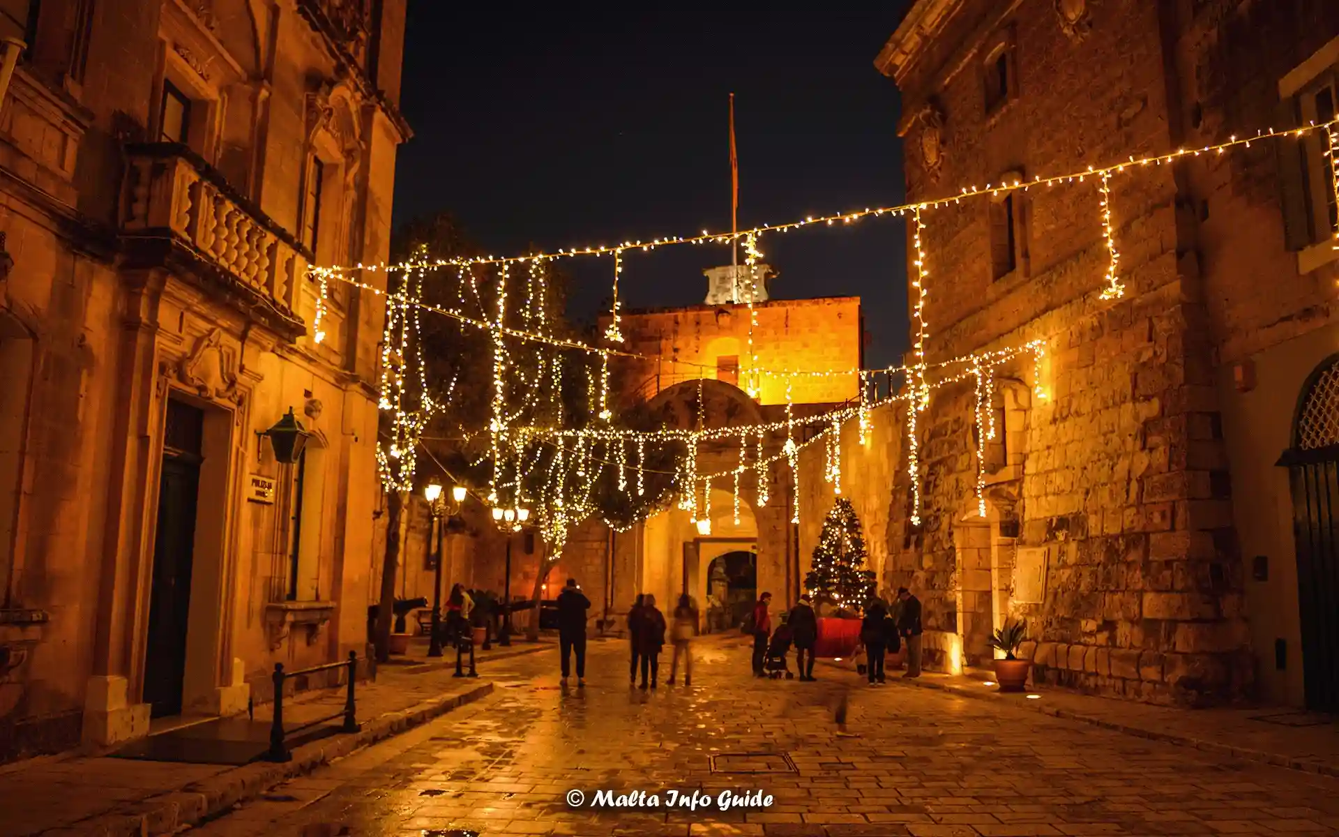 Festive lights illuminate the entrace to Mdina, Malta, at night.