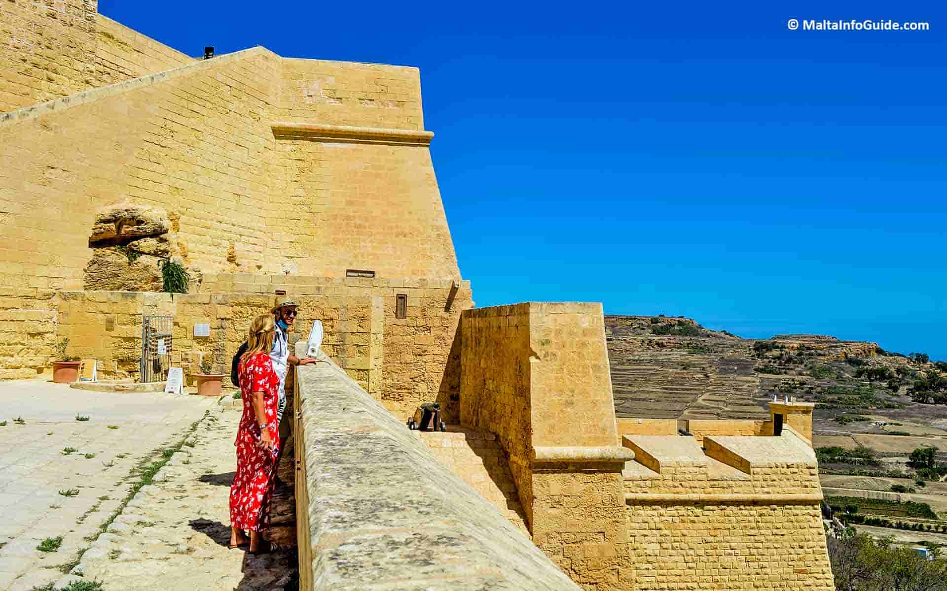 Two tourists looking at the view from the fortifications of the Citadel in Gozo.