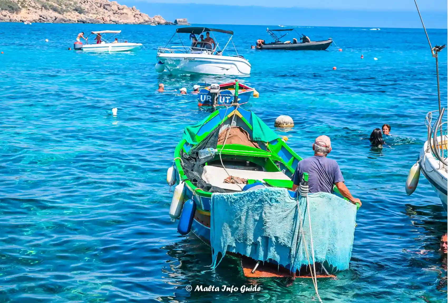 Traditional fishing boat moored among swimmers at Dahlet Qorrot.
