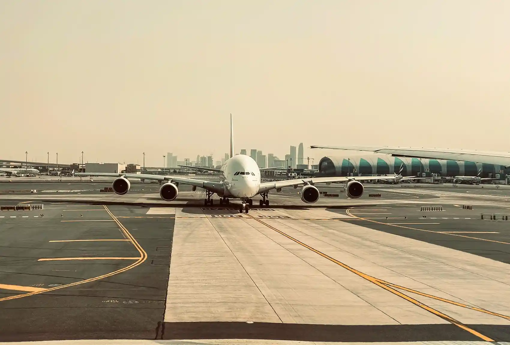 Dubai International Airport runway with Airbus A380 and Dubai skyline.
