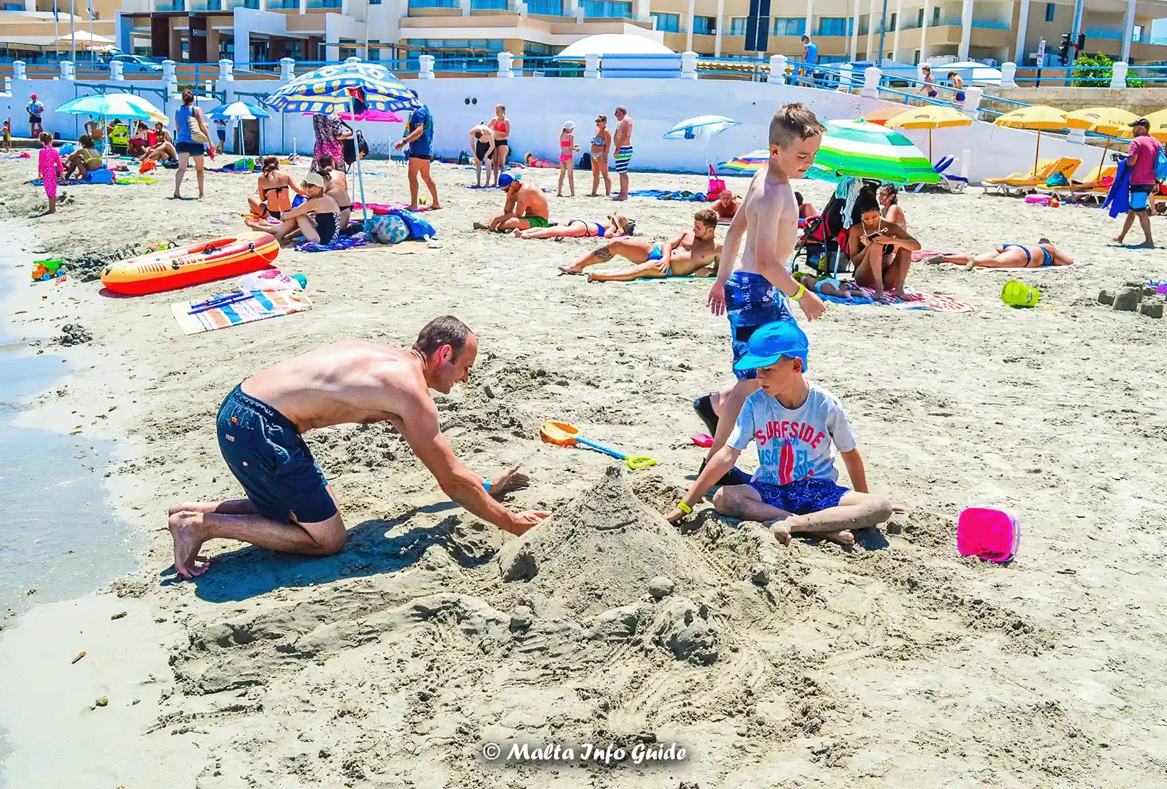 Family building sandcastles together on Mellieha Bay beach Malta.
