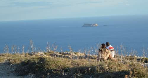 Couple sitting on the rocks looking at Filfla