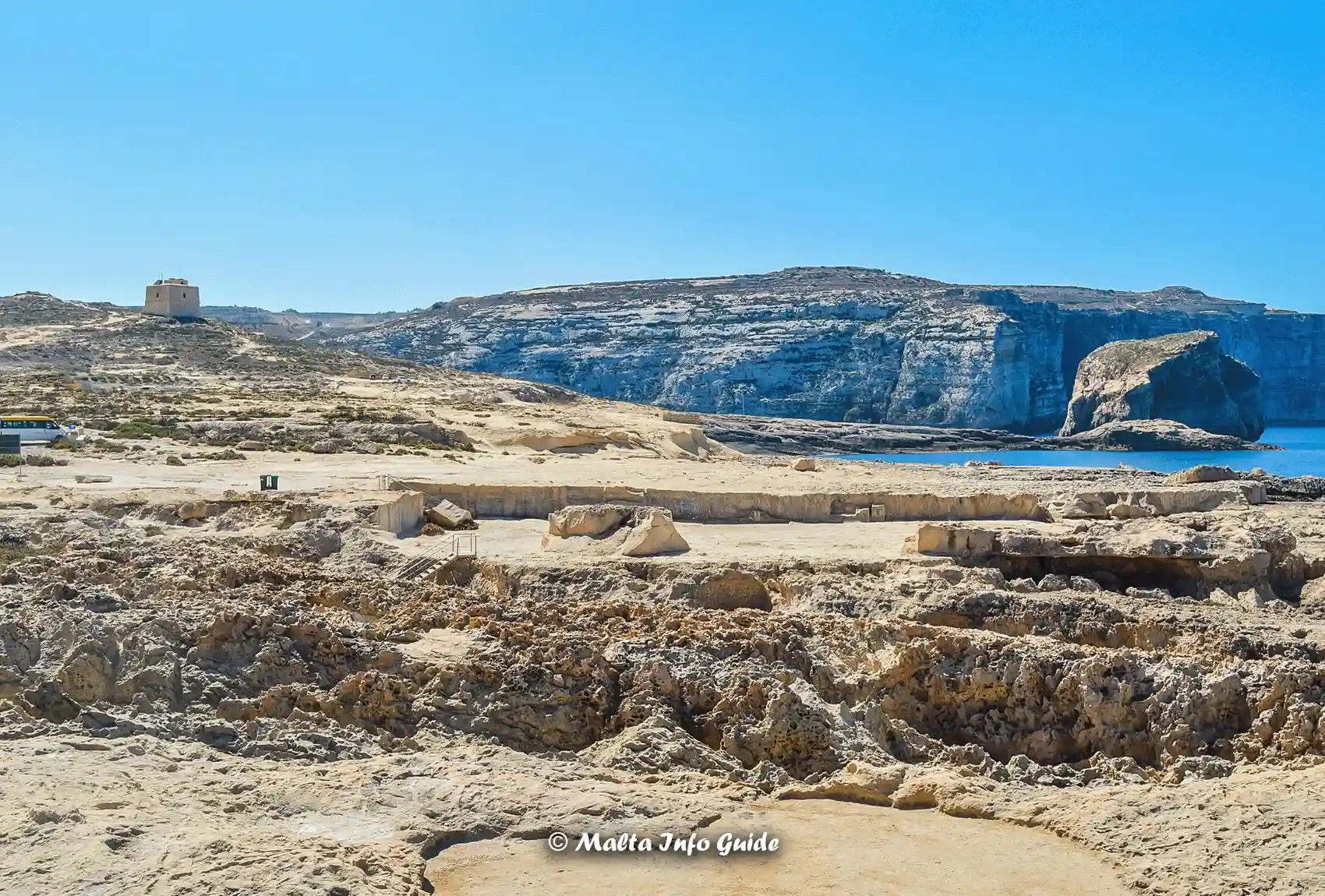 Rugged landscape and historical Dwejra Tower on Gozo's coastline.