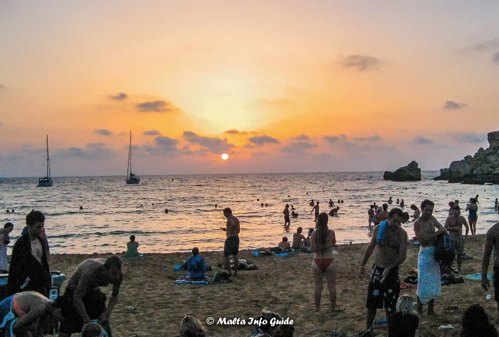 Visitors watch sunset from Għajn Tuffieħa Bay beach.