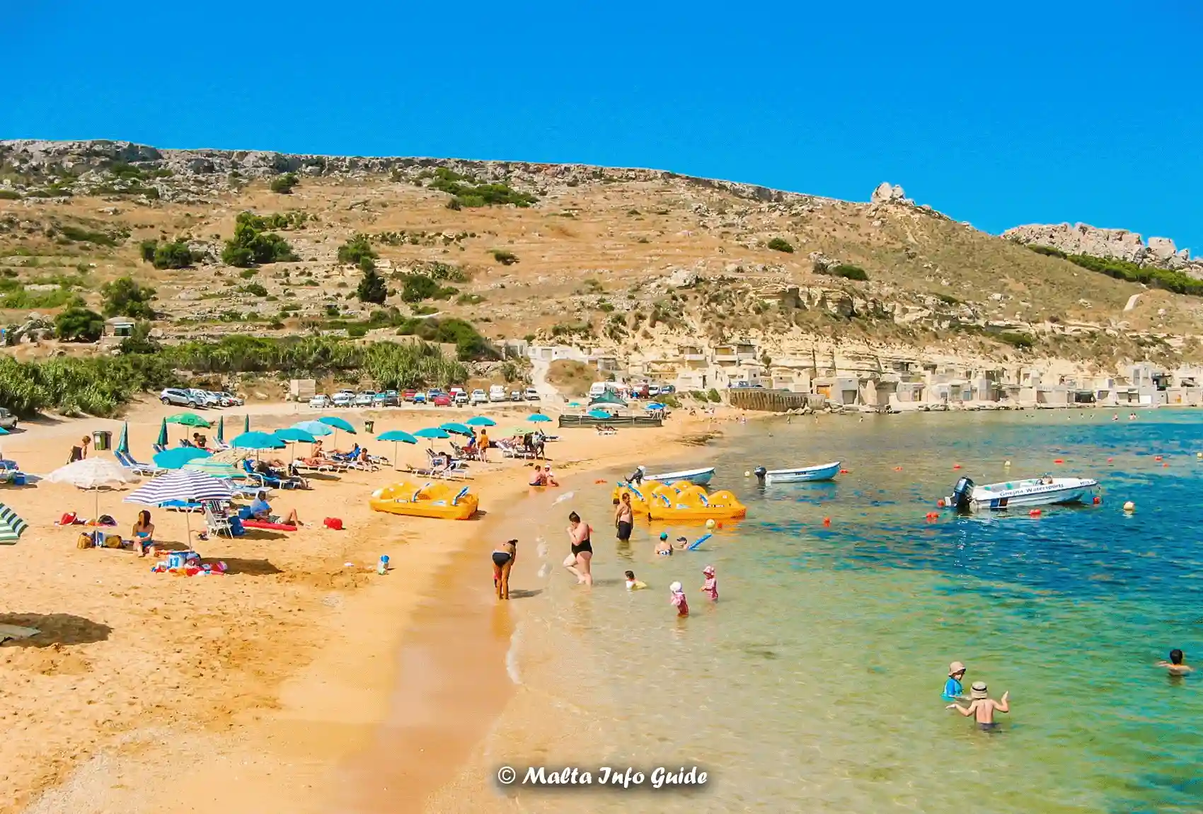 Families swimming in shallow water at Gnejna Bay.