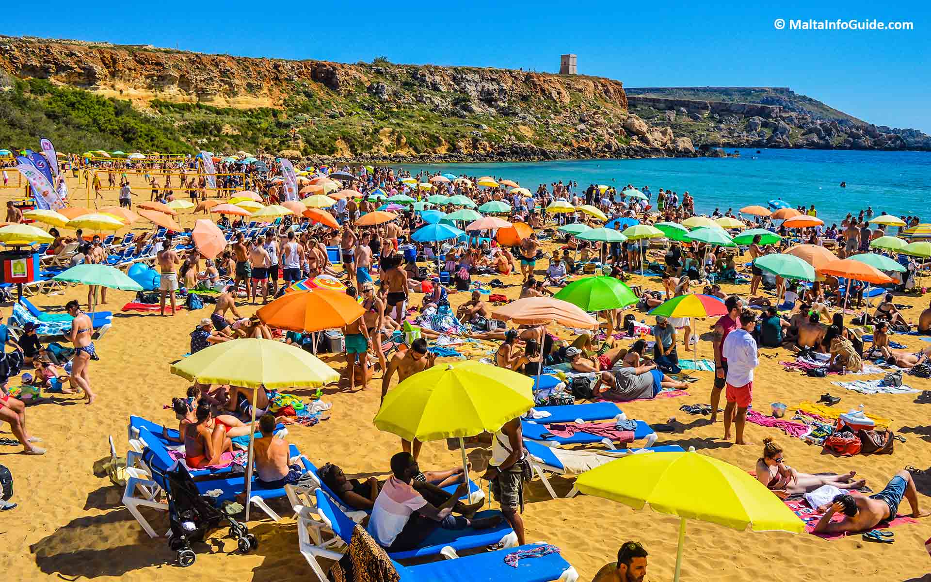 Golden Bay is packed with people sunbathing and swimming.