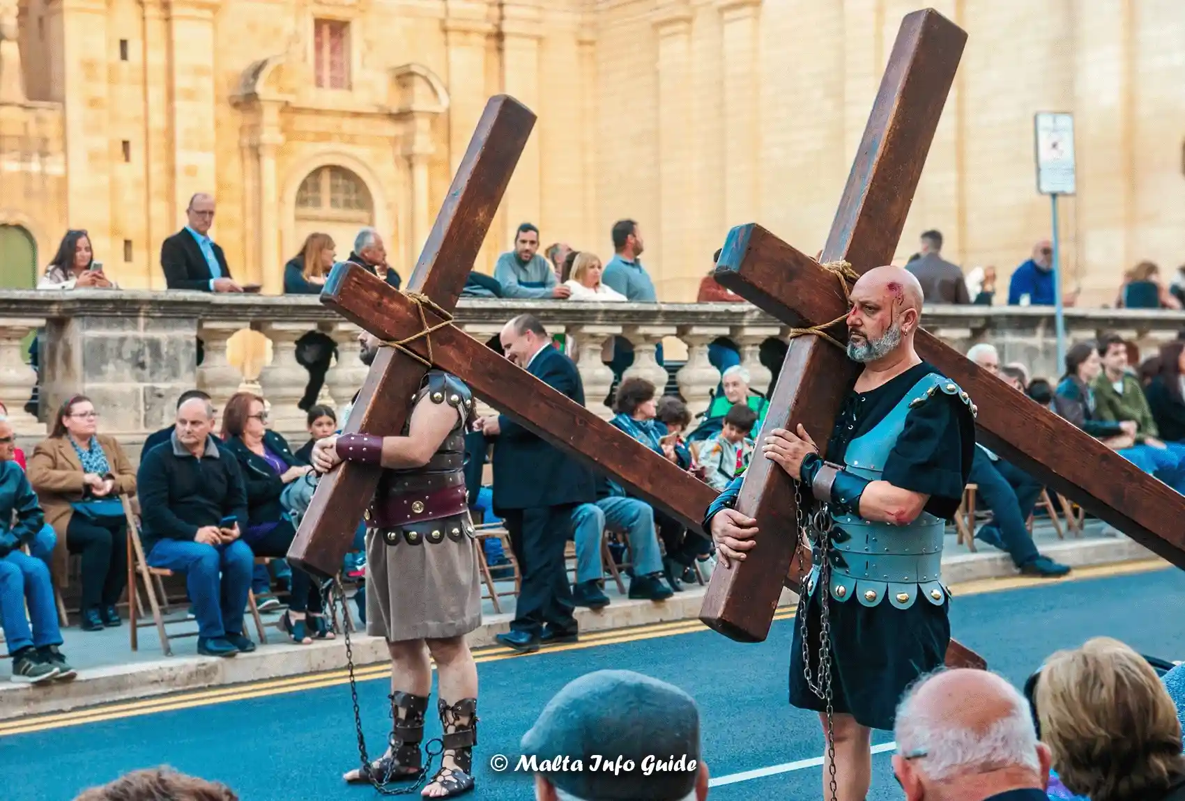 Two men walking along the Good Friday Procession holding wooden crosses. The Good Friday Procession in Zejtun Malta.