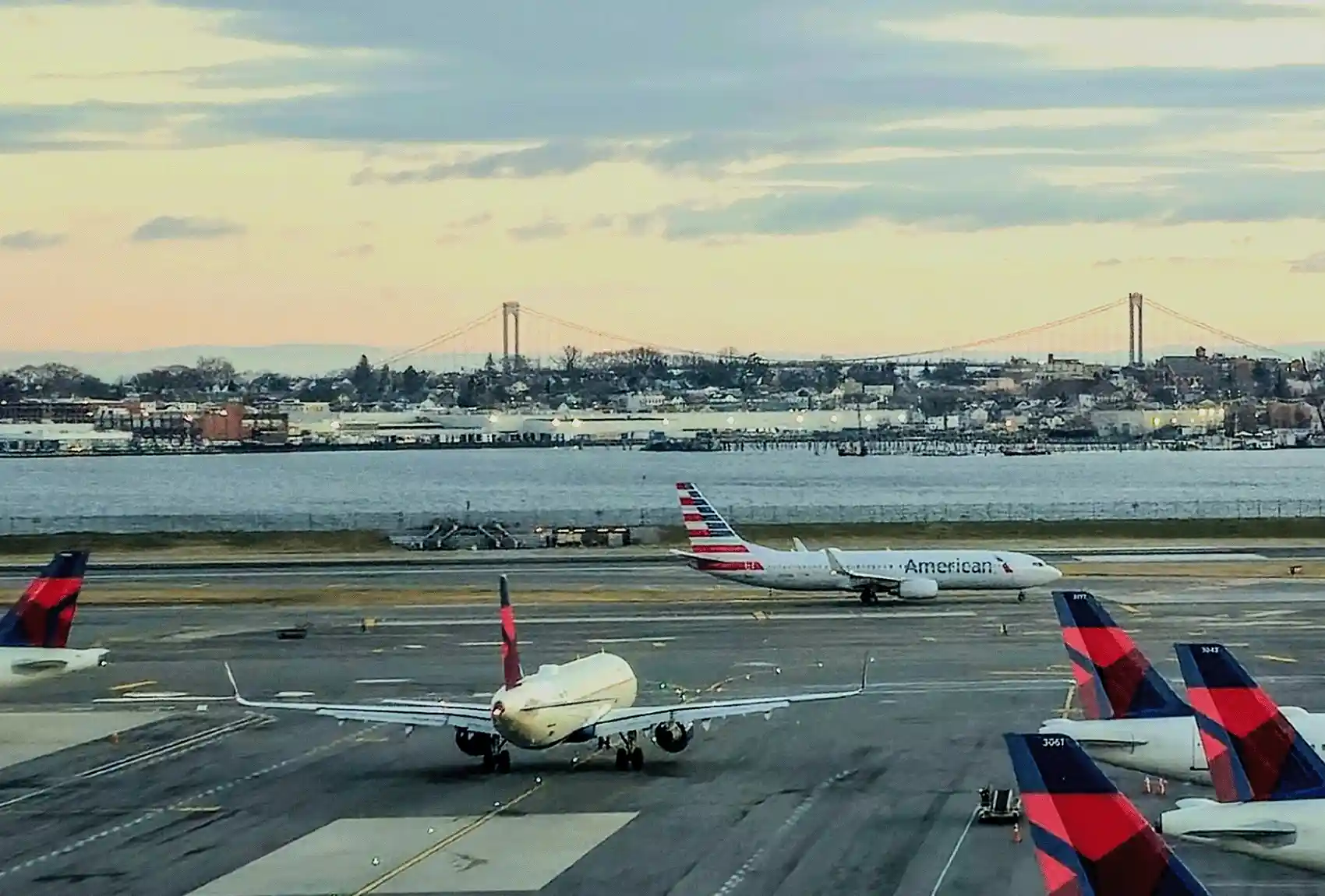 LaGuardia Airport runway with aircraft and Whitestone Bridge in the distance.