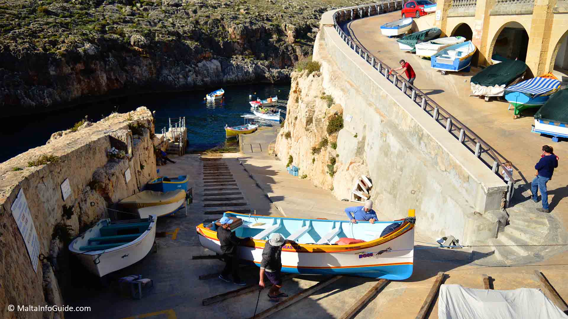 2 locals pulling up a traditional fishing boat at Blue Grotto Malta