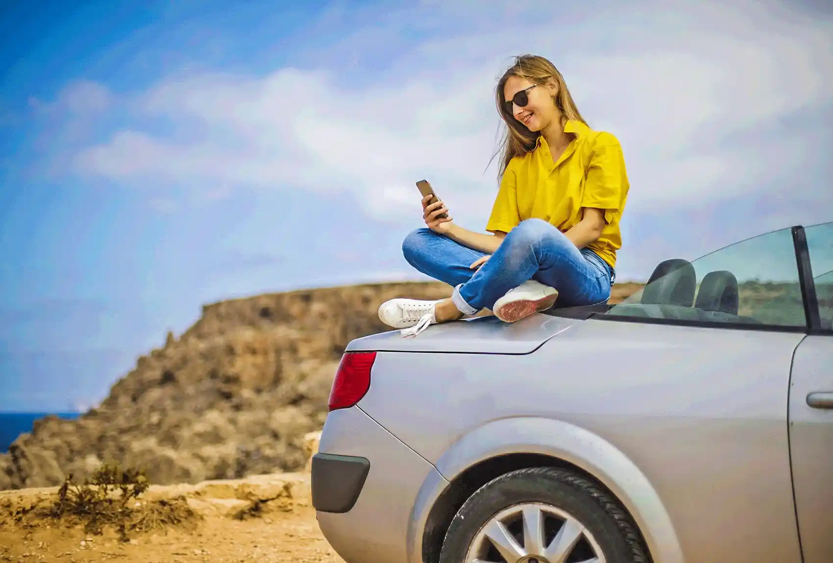 Traveller sitting on car during a Malta road trip.