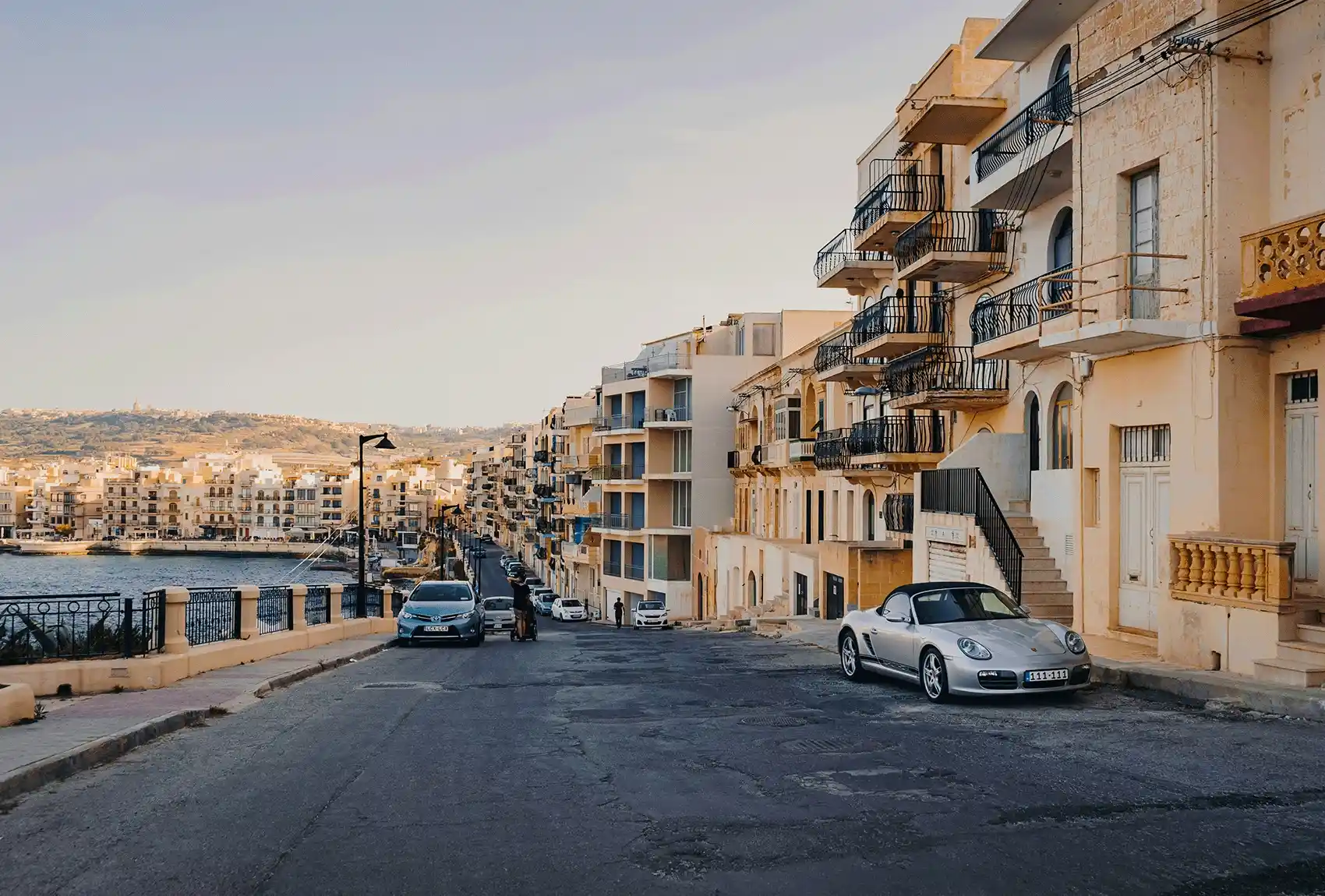 Car parked beside a quiet coastal Marsalforn Gozo street.