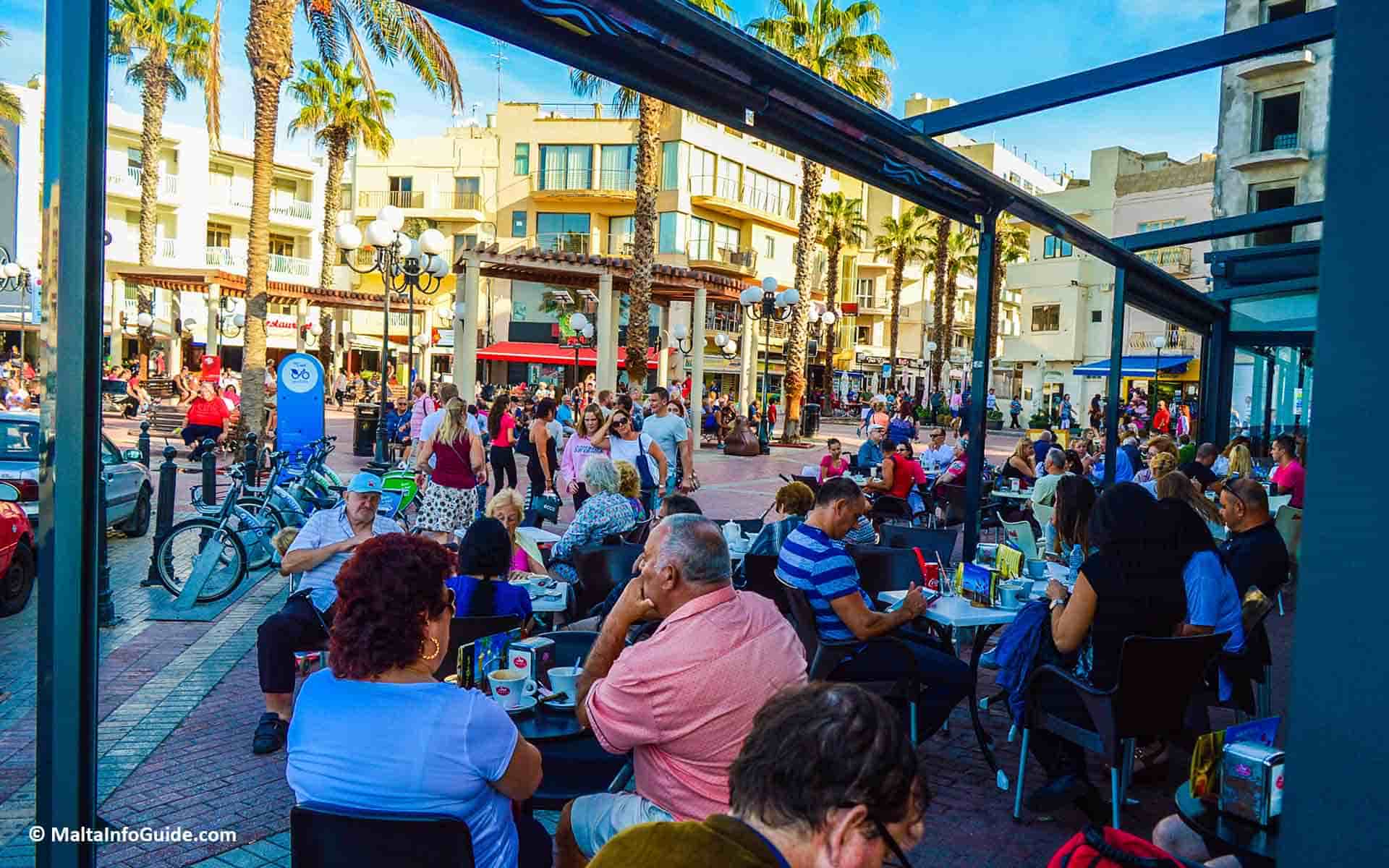 People eating at restaurants at Bugibba square.