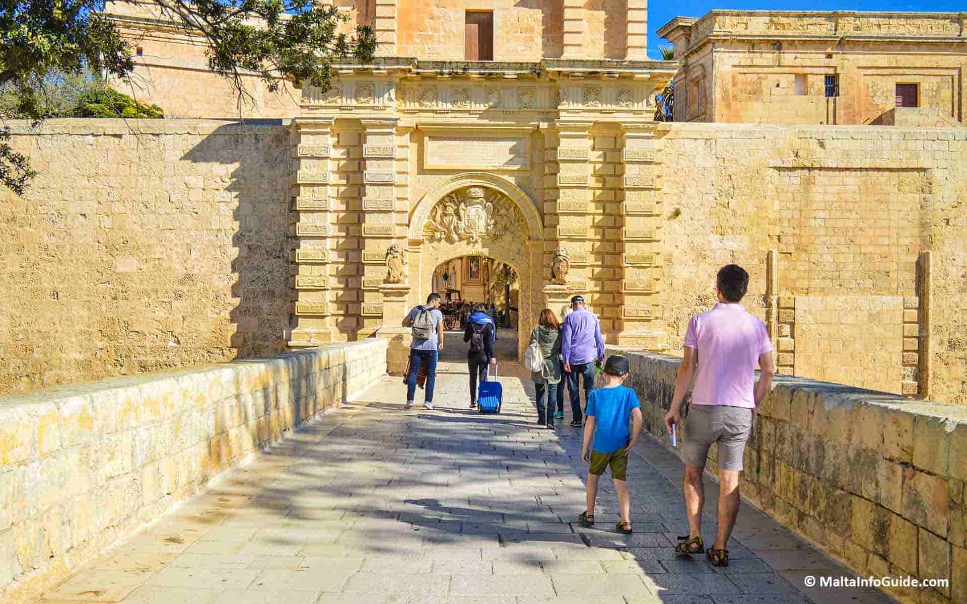 People walking on the bridge and entering Mdina Gate Malta.