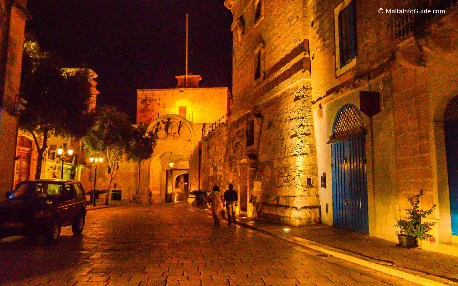 Two people walking out of Mdina at night.