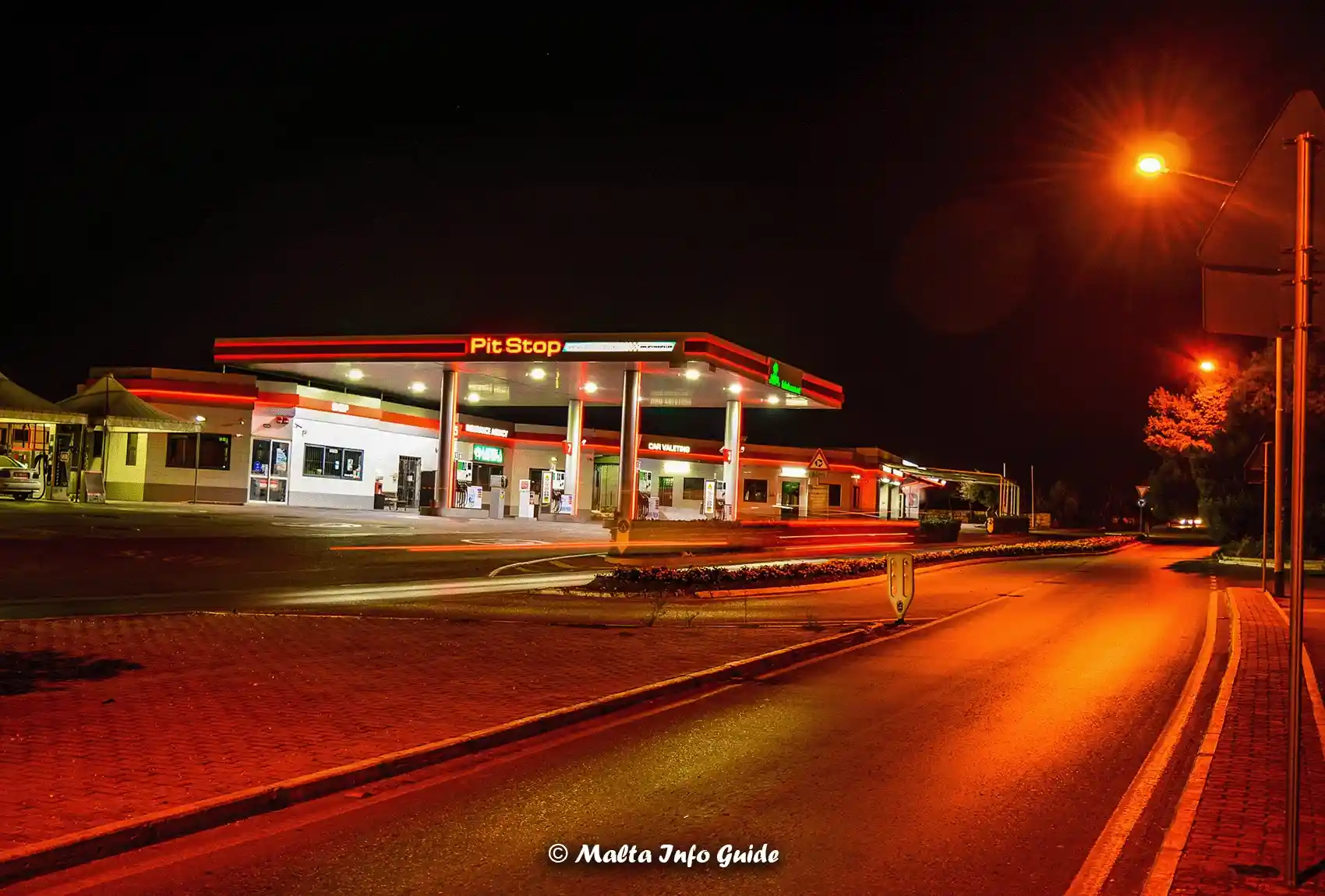 Pit Stop petrol station beside road at night.