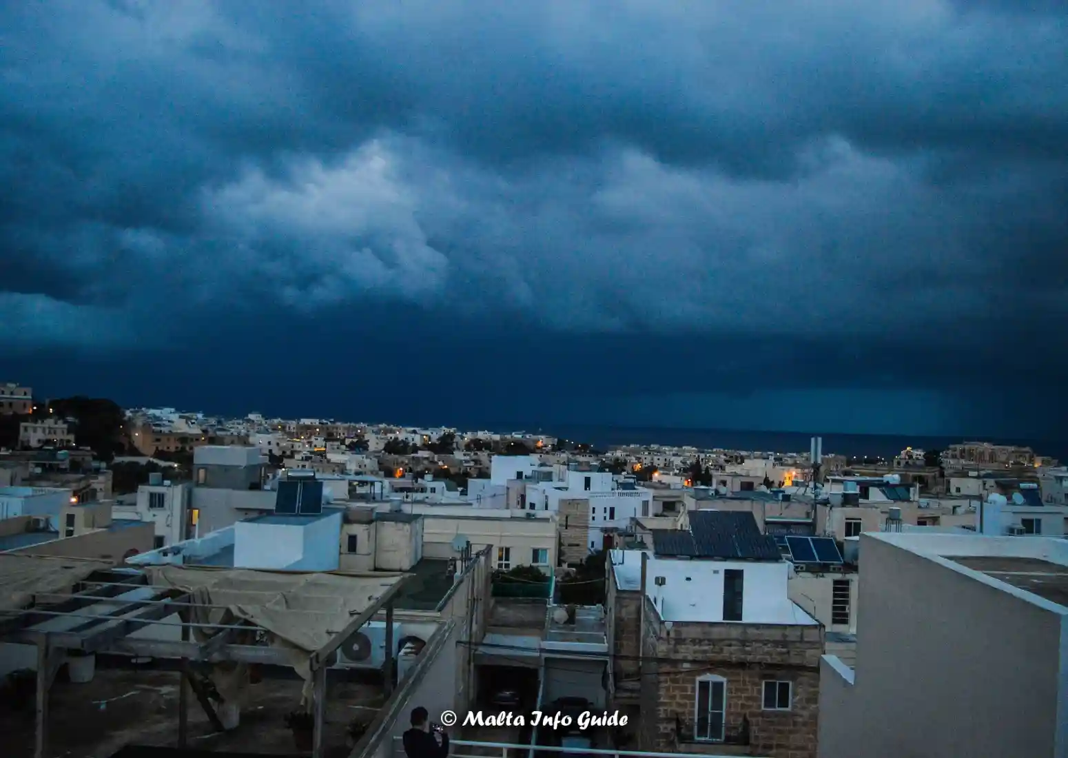 Dark storm clouds gathering over Maltese rooftops.