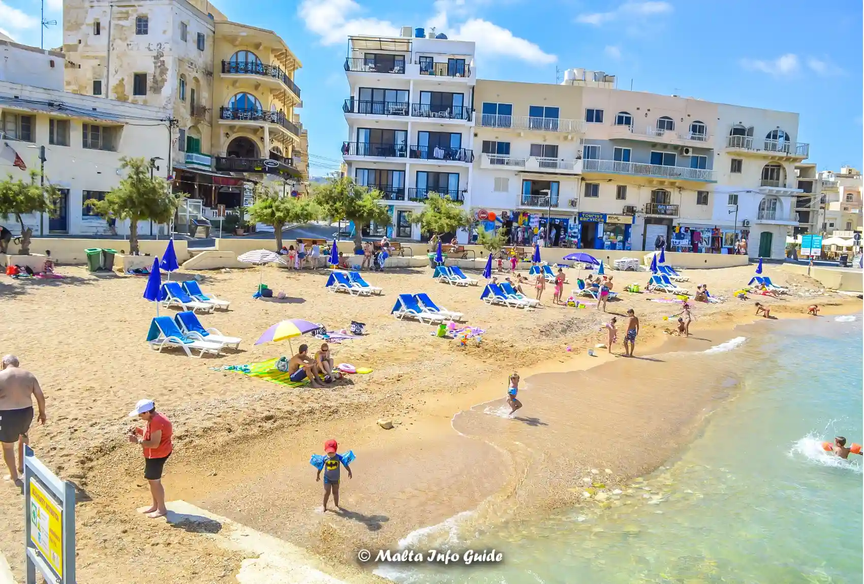 Marsalforn sandy beach with swimmers beside the waterfront.