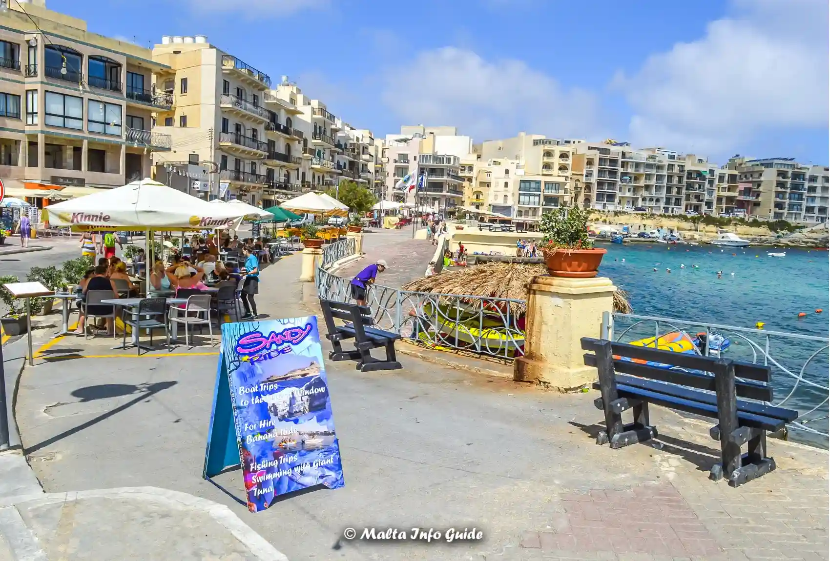 Waterfront restaurants and benches overlooking busy Marsalforn Bay.
