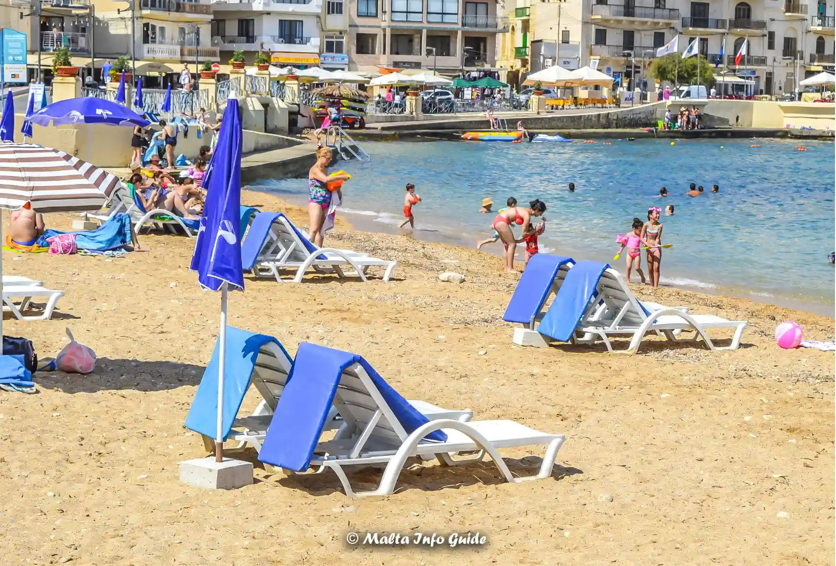 Sunbeds and families along sandy Marsalforn Bay beach.