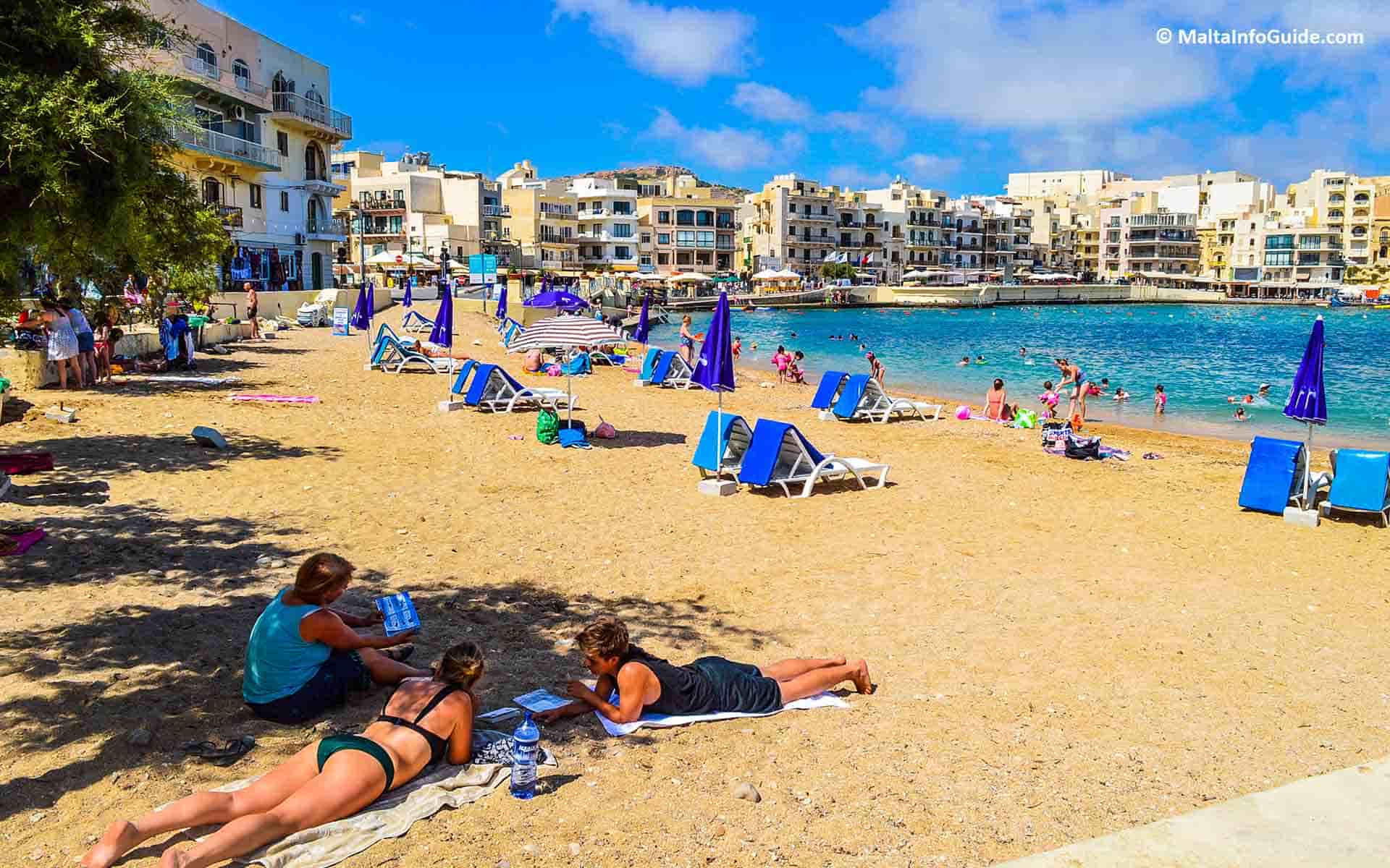 People sunbathing on Marsalforn Bay Malta.