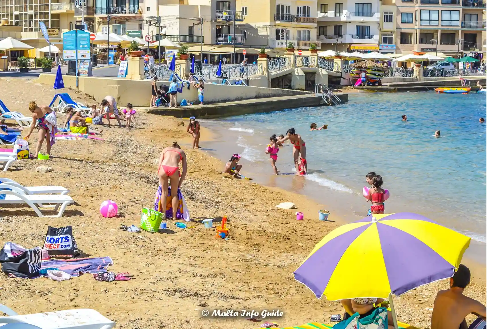 Families relax on Marsalforn Bay's small sandy Gozo beach.