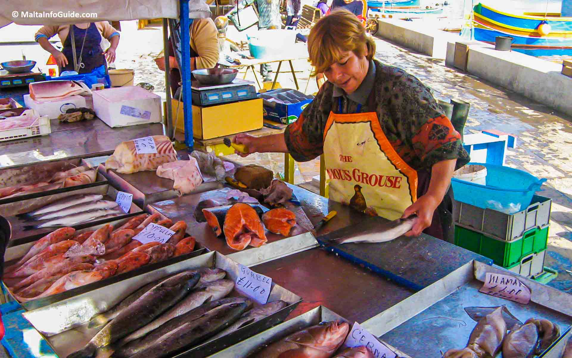 A woman street hawker cutting fresh Maltese fish.