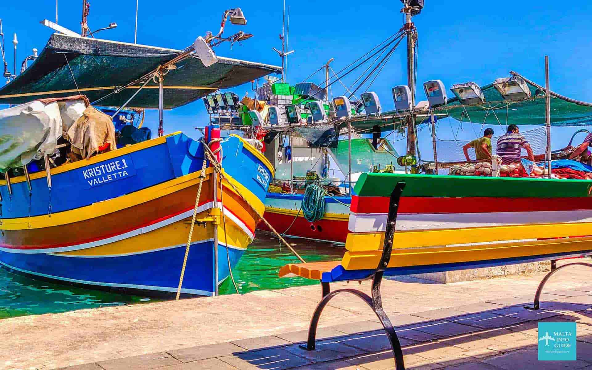 Beautiful colours popping from the Luzzu boat and bench in front of the sea at Marsaxlokk Malta.