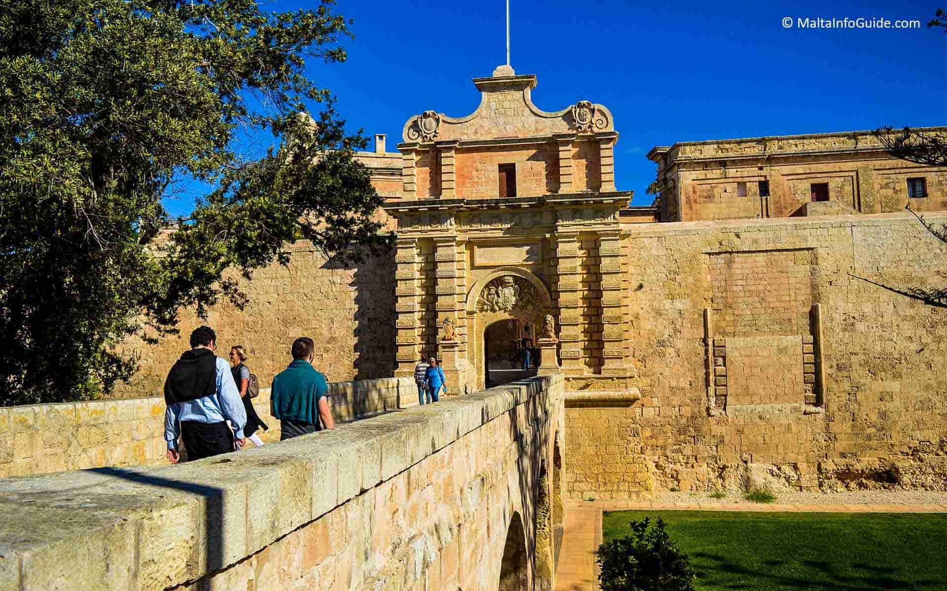 People walking on the bridge to Mdina Gate.