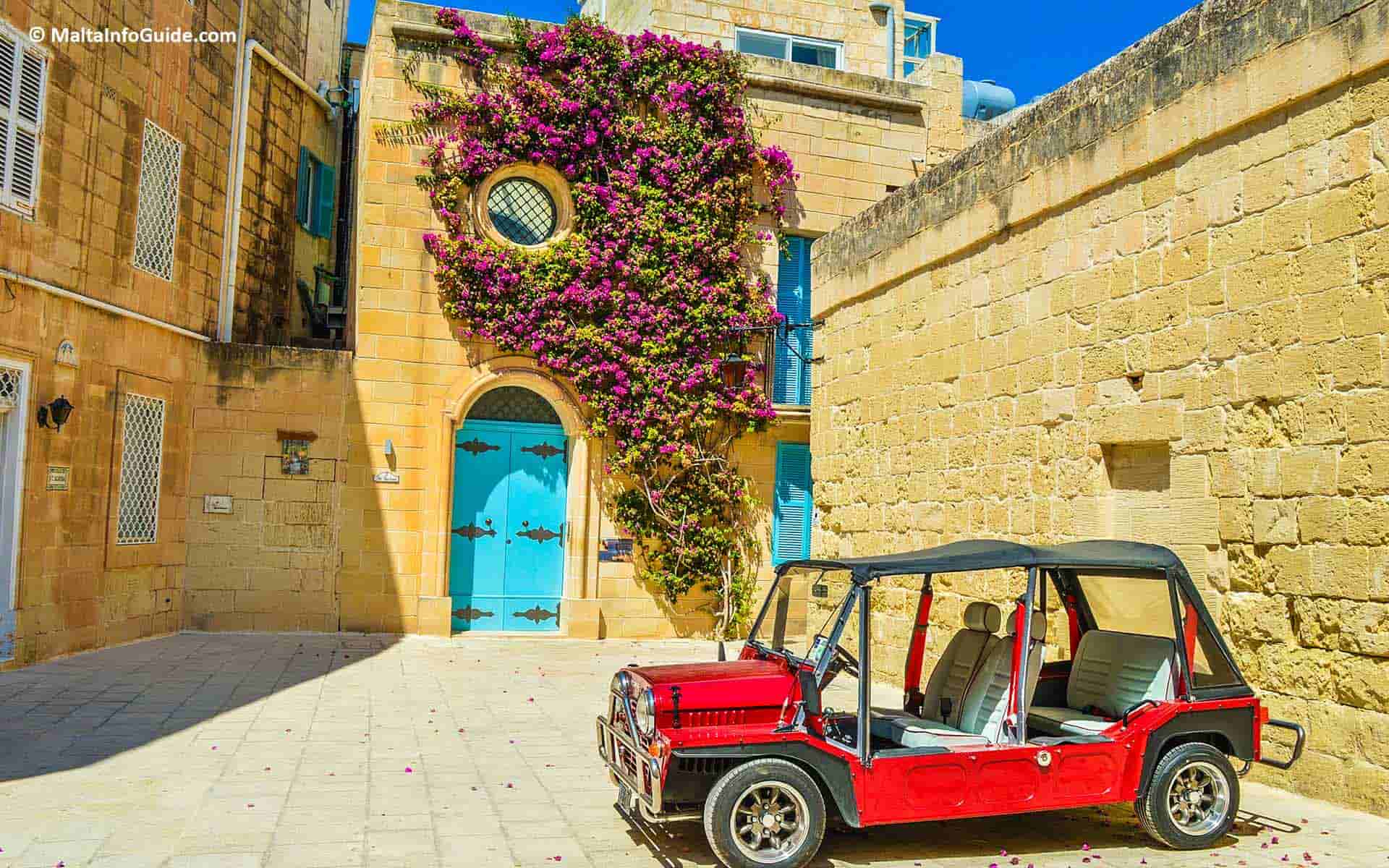 A townhouse in the heart of Mdina Malta with an antique car parked beside it.