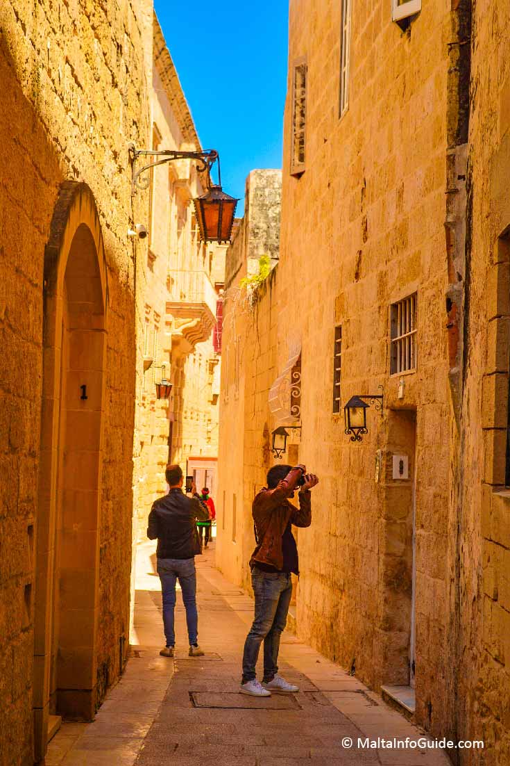 People taking photos of narrow street in Mdina Malta