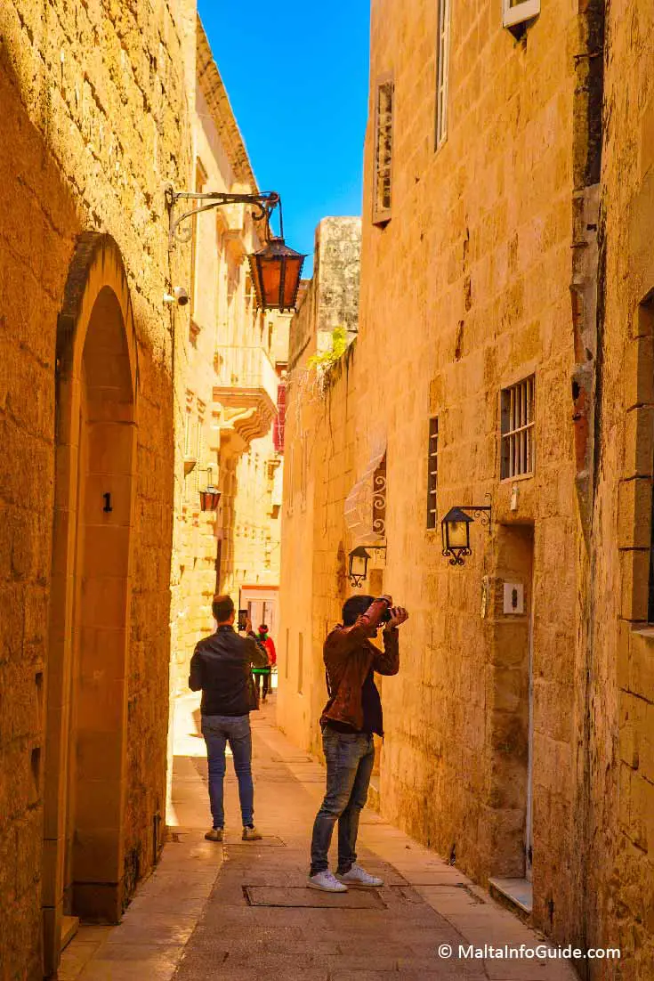 People taking photos of narrow street in Mdina Malta
