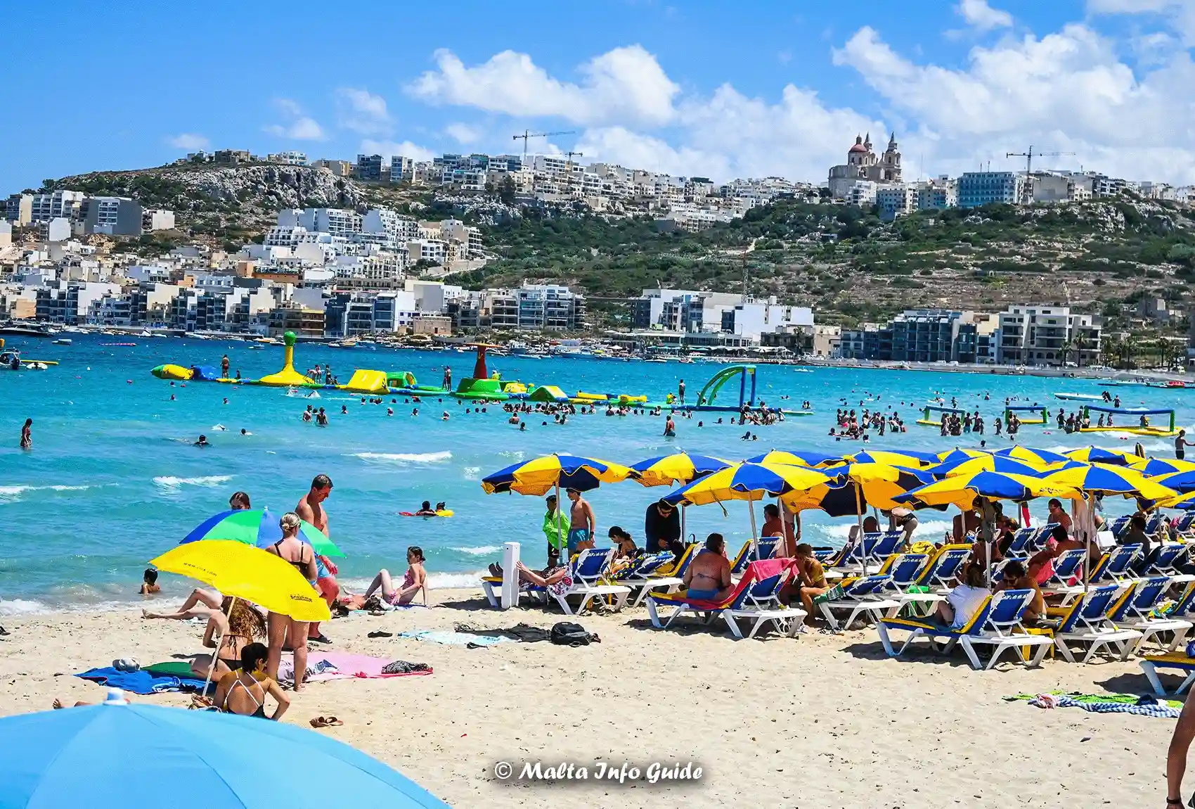 Busy swimmers enjoy shallow water at Mellieha Bay beach.