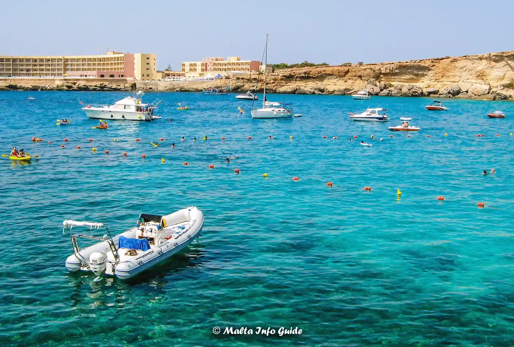 Boats anchored beyond swimmers in clear Paradise Bay waters.
