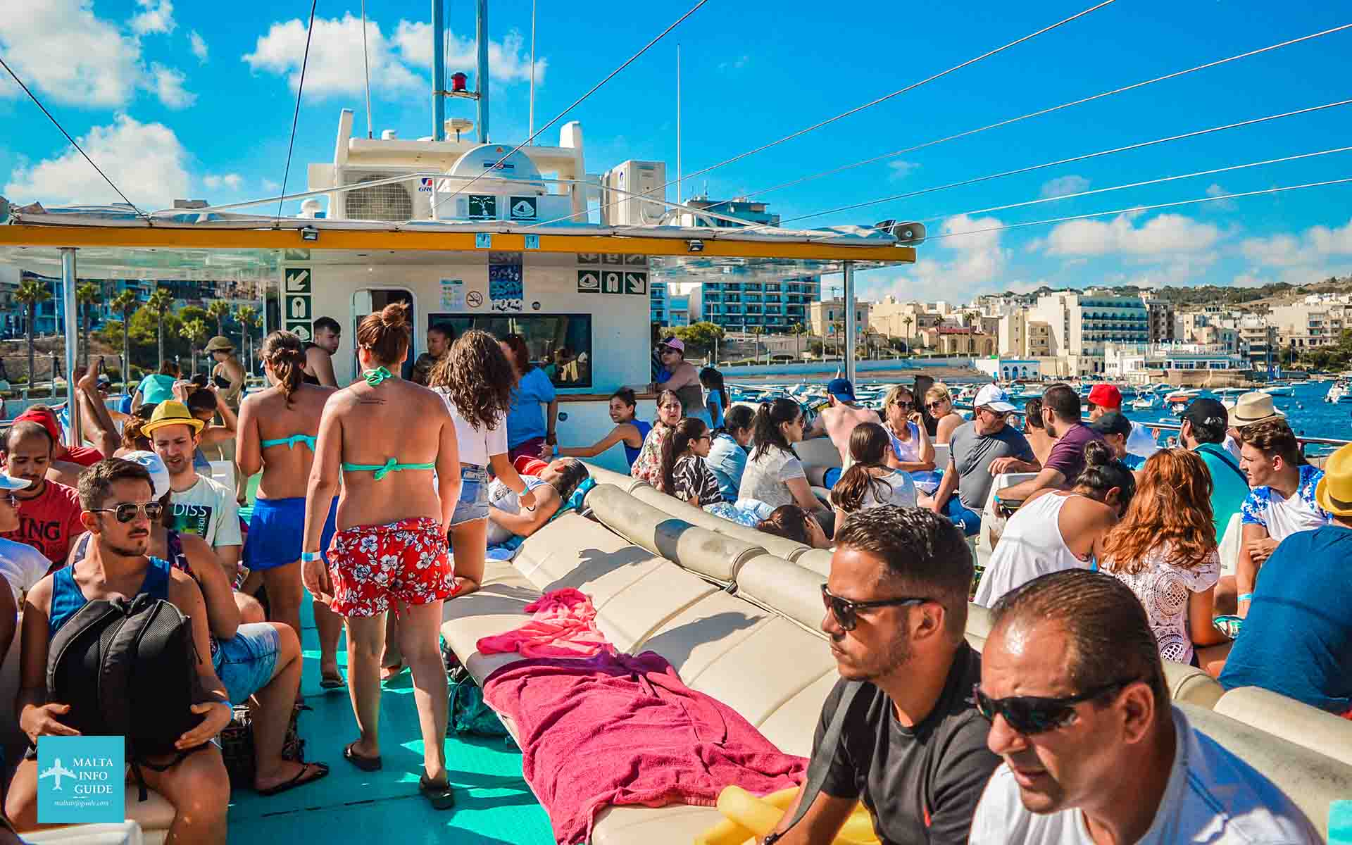 Pasażerowie siedzący na górnym pokładzie katamaranu w drodze do Blue Lagoon Comino