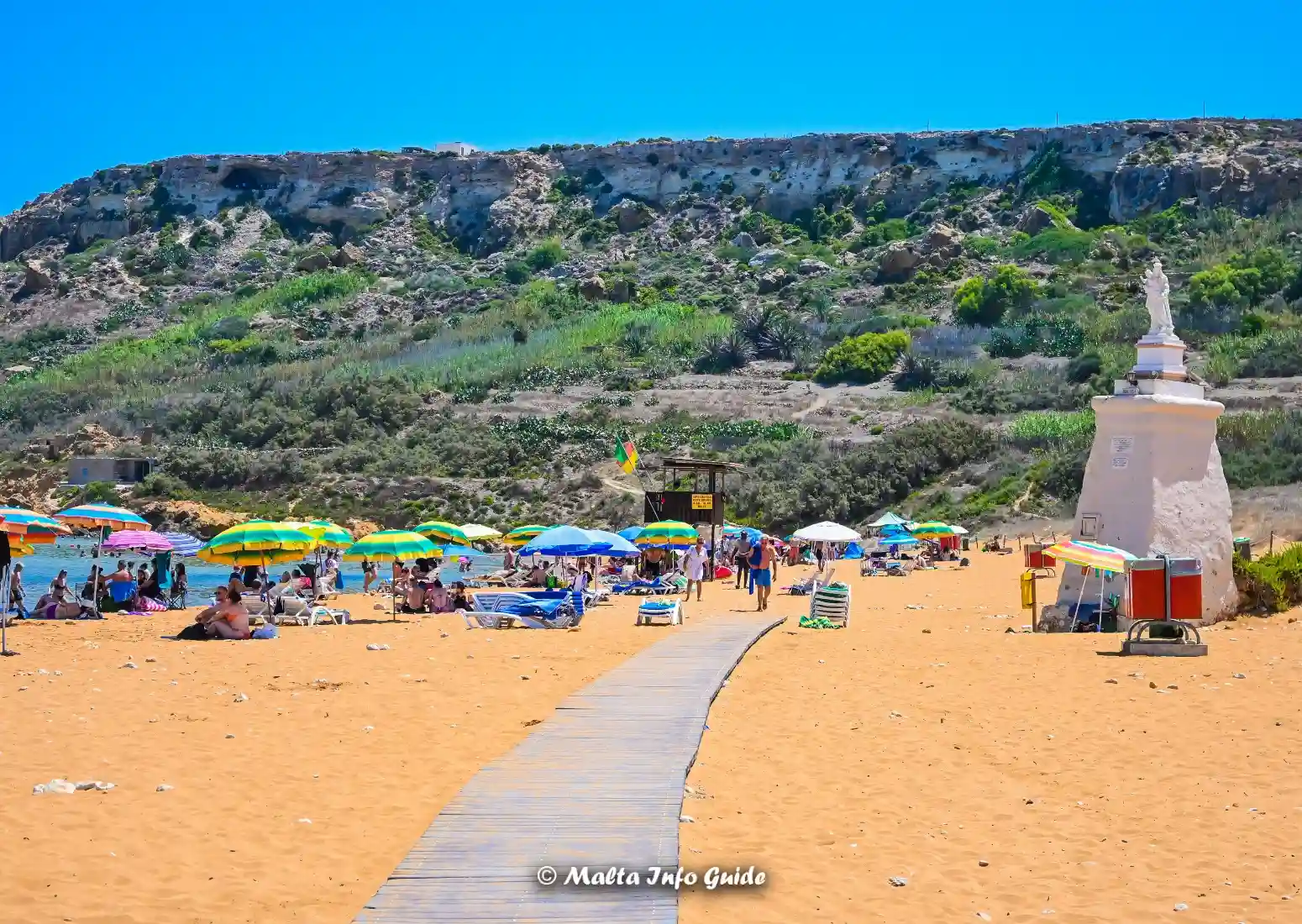 Ramla Bay's red-sand beach with sunbeds and umbrellas in Gozo, Malta.