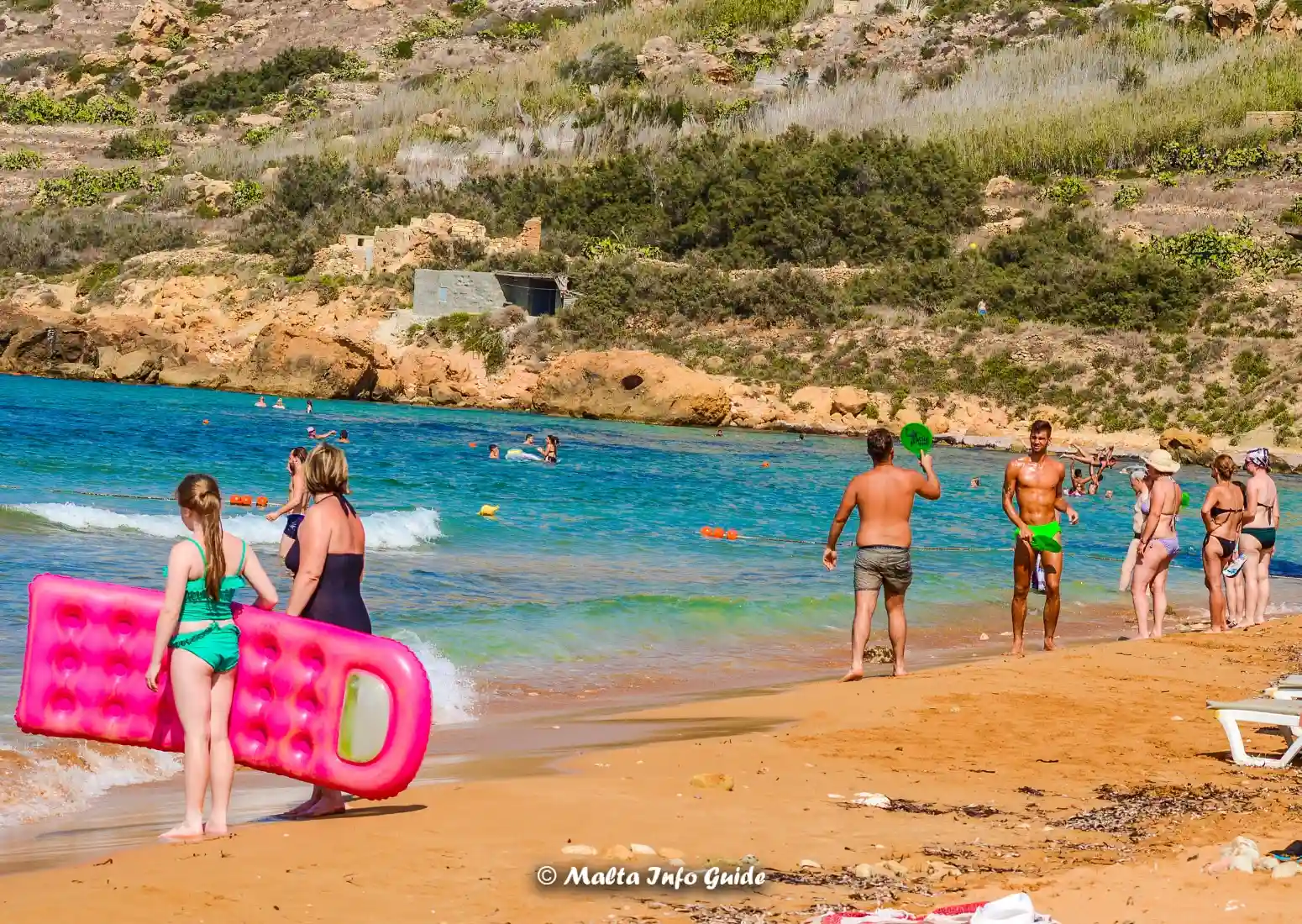 Visitors are swimming and relaxing at Ramla Bay beach in Gozo, Malta.