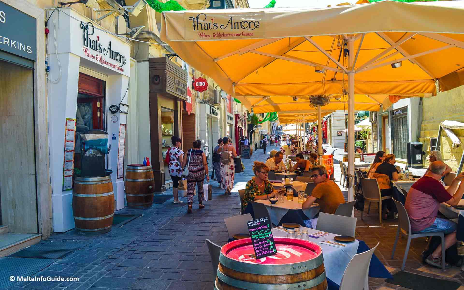 People eating at outdoor restaurants at Merchant Street in Valletta.