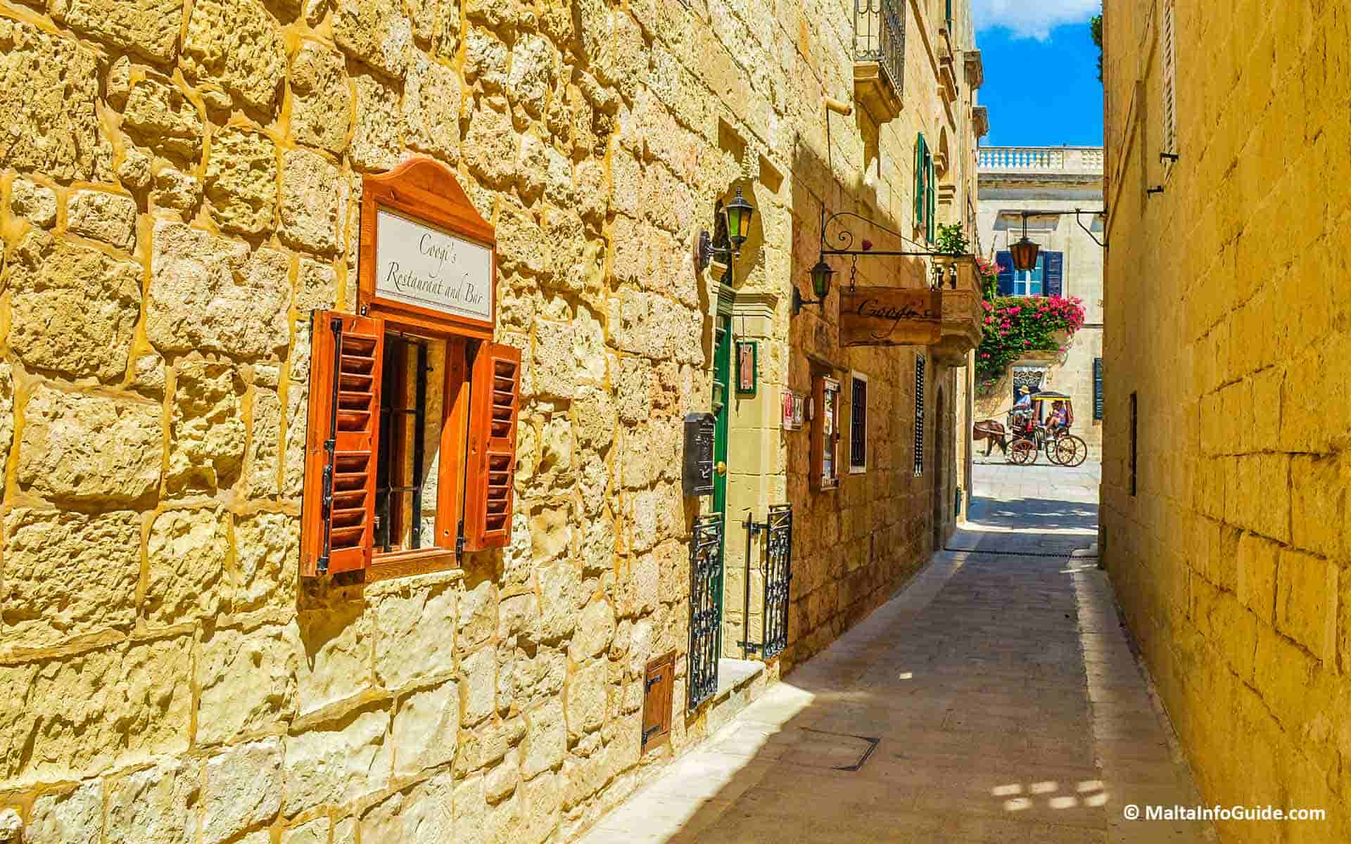 A restaurant in a narrow street with a karozzin seen passing by at the end of the narrow street. A restaurant in a narrow street with a karozzin seen passing by at the end of the narrow street.