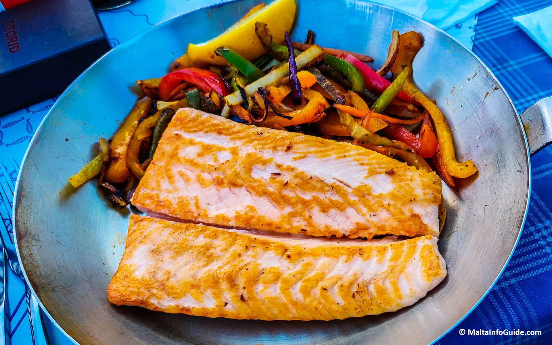 A salmon dish with vegetables on the side.