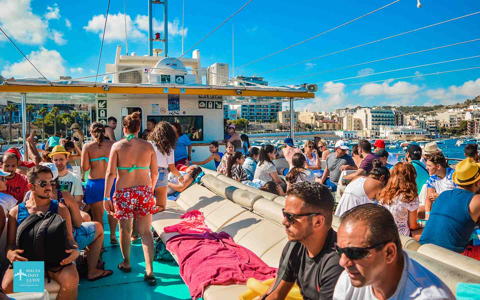 Passengers seated on the upper deck of the catamaran on the way to Blue Lagoon Comino