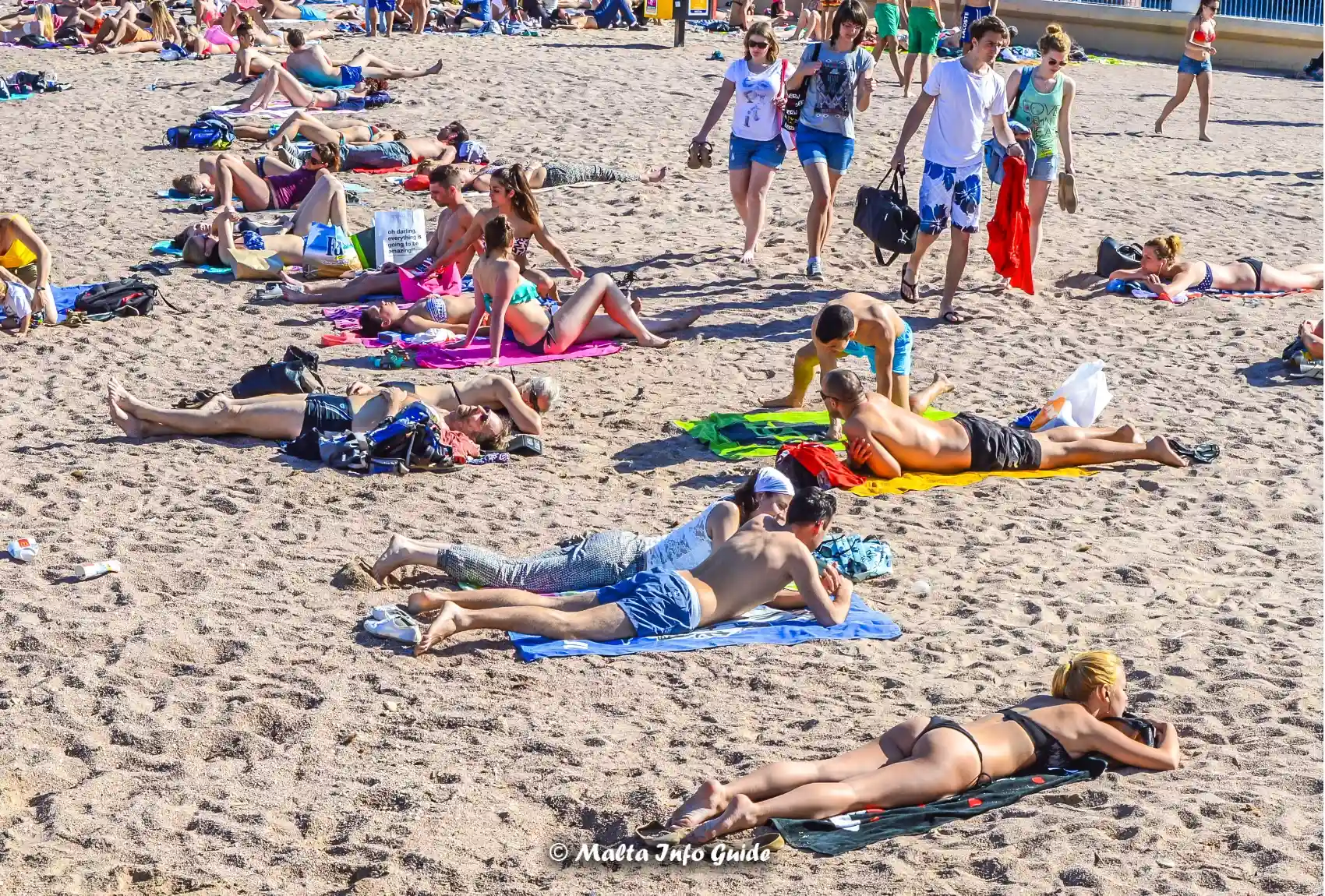 Visitors relaxing on crowded St George's Bay sandy beach.