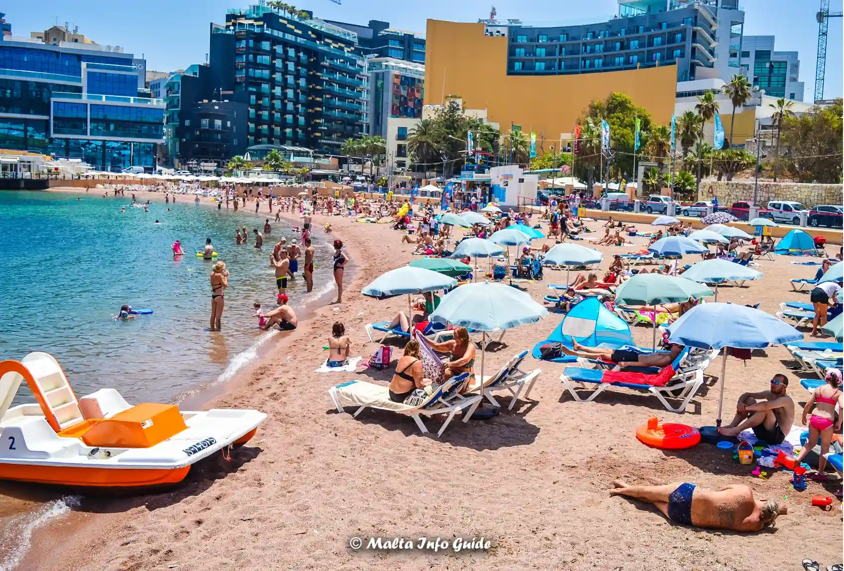 Sunbathers and swimmers along St George's Bay shoreline.