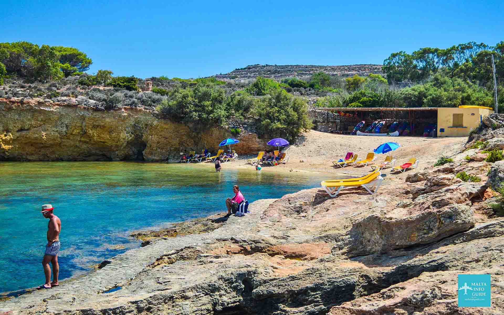 People swimming and subathing at St. Nicholas Bay on the island of Comino.